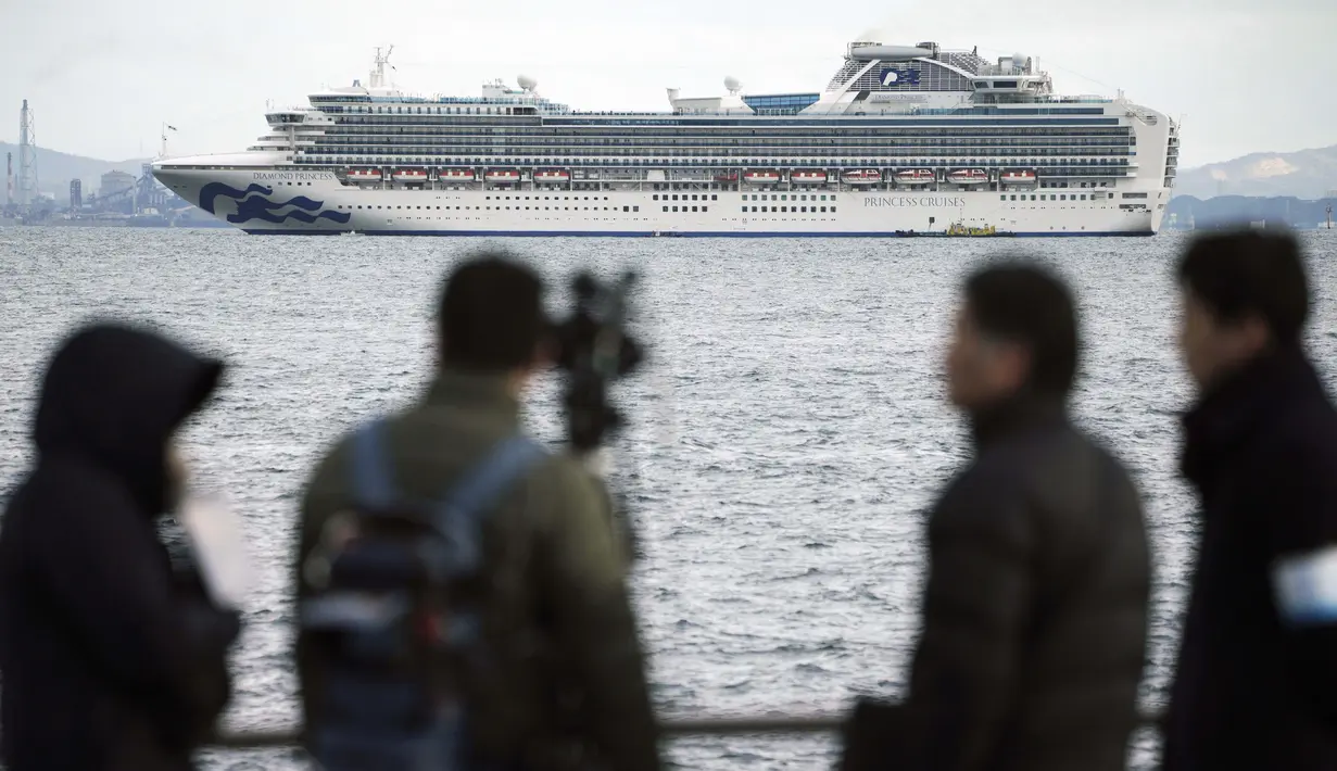 Seorang kru TV memfilmkan sebuah kapal pesiar Diamond Princess berlabuh di Pelabuhan Yokohama di Yokohama, Tokyo (4/2/2020). Otoritas Kesehatan Jepang mengkarantina 3.700 orang di dalam sebuah kapal pesiar setelah satu penumpang dinyatakan positif terkena virus corona.  (AP Photo/Eugene Hoshiko)
