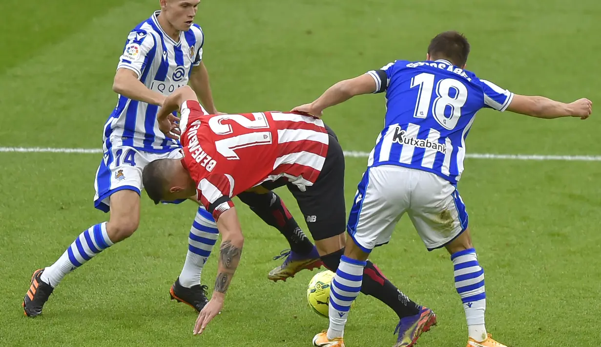 Pemain Athletic Bilbao, Alejandro Berenguer, berusaha melewati pemain Real Sociedad pada laga liga Spanyol di Stadion San Mames, Kamis (31/12/2020). Real Sociedad menang dengan skor 1-0. (AFP/Ander Gillenea)