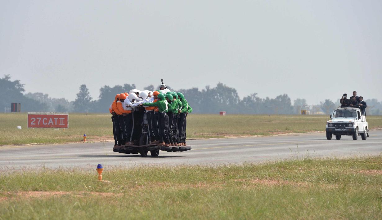 Aksi anggota Tornado dari Army Service Corps (ASC) membawa 58 orang dengan satu motor 500 cc di Bangalore (19/11). Tim Tornado memecahkan rekor sebelumnya dari 56 pria yang dimenangkan Army Signal Corps (Daredevils) pada 2010. (AFP Photo/Manjunath Kiran)