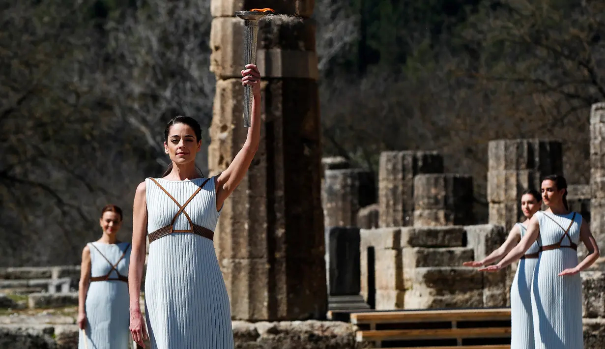 Aktris Yunani Xanthi Georgiou sebagai Imam Besar memegang obor saat upacara penyalaan api Olimpiade Tokyo 2020 di Kota Tua Olympia, Yanani, Kamis (12/3/2020). (AP Photo/Thanassis Stavrakis)