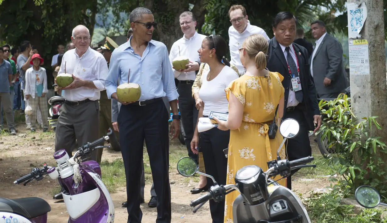 Presiden AS, Barack Obama memegang kelapa bersama duta besar AS untuk Laos Daniel Clune saat ia membuat kejutan ke warga Laos untuk berhenti meminum kelapa di sepanjang Sungai Mekong di Luang Prabang, Laos (7/9). (AFP PHOTO/SAUL Loeb)