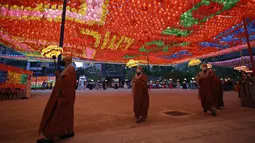 Biksu dan pengikutnya mengenakan masker sambil menjaga jarak sosial sebagai pencegahan terhadap virus corona membawa lampion di kuil Jogye, Seoul, Korea Selatan (6/5/2021). Di negeri Ginseng ini, ulang tahun Buddha dirayakan dengan menggelar ‘Lotus Lantern Festival’. (AP Photo/Lee Jin-man)