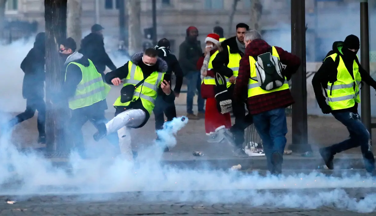 Demonstran menendang tabung gas air mata saat kerusuhan menentang kenaikan harga bahan bakar di Paris, Prancis, Sabtu (24/11). Polisi menggunakan gas air mata dan meriam air untuk membubarkan demonstran. (AP Photo/Christophe Ena)