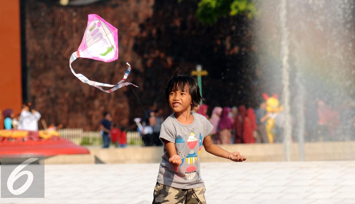 Seorang anak berusaha menerbangkan layang layang saat bermain di Lapangan Monumen Tugu Pancasila TMII, Jakarta, Jumat (8/7). TMII masih menjadi lokasi favorit warga menghabiskan libur hari raya. (Liputan6.com/Helmi Fithriansyah)