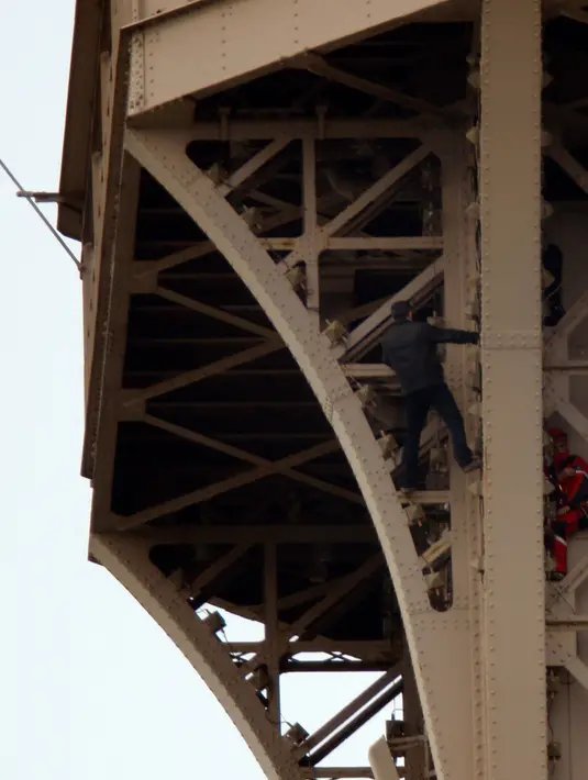 Petugas pemadam kebakaran berusaha mendekati seorang pria yang memanjat Menara Eiffel tanpa peralatan keselamatan di Paris, Senin (20/5/2019). Pria tersebut berhasil pemanjat yang dievakuasi dan ditahan setelah bertahan selama enam jam di monumen kenamaan Kota Paris itu. (REUTERS/Charles Platiau