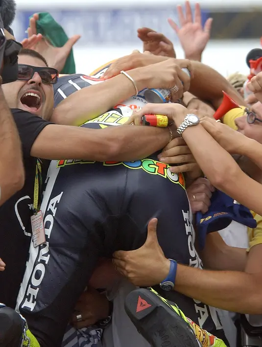 Pria tampan berusia 36 tahun ini memang tidak membatasi dirinya dengan penggemar. Valentino Rossi pun rela dikerumuni serta dipeluk oleh penggemar untuk merayakan kemenangan bersama. (AFP/Bintang.com)