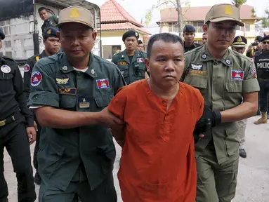 Yem Chrin (tengah) dikawal oleh petugas polisi saat tiba di Pengadilan Provinsi Battambang,Kamboja,Kamis (3/12). Pengadilan Kamboja menghukum Yem Chrin  25 tahun penjara dengan kasus pembunuhan dan penyebaran HIV lebih dari 270 orang. (REUTERS/Stringer)