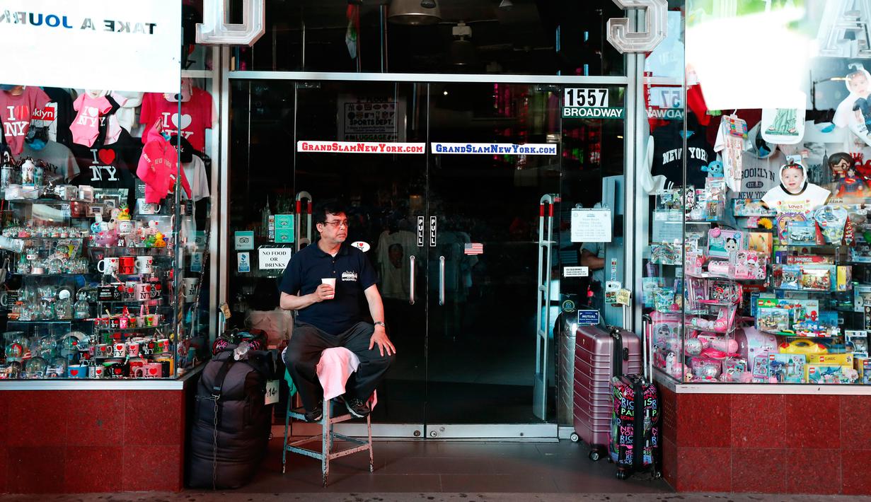 Seorang pemilik toko duduk di luar tokonya selama pemadaman listrik di Times Square, New York, AS, Sabtu (13/7/2019).  Pemadaman listrik juga mempengaruhi bagian barat Manhattan, khususnya kawasan Hell's Kitchen dan teater Broadway. (AP Photo/Michael Owens)
