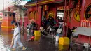 Masyarakat Tionghoa melintasi genangan air di Vihara Dharma Bakti, Petak Sembilan, Jakarta, Kamis (19/2/2015). Hujan deras yang mengguyur kawasan tersebut sekitar pukul 11.30 WIB membuat halaman depan vihara tergenang. (Liputan6.com/Andrian M Tunay)