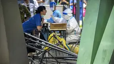 Seorang pekerja yang mengenakan pakaian pelindung menyeka tenggorokan seorang wanita untuk tes COVID-19 di tempat pengujian virus corona di Beijing, Rabu (6/7/2022). Warga beberapa bagian Shanghai dan Beijing telah diperintahkan untuk menjalani tes massal COVID-19 lebih lanjut menyusul ditemukannya kasus baru di dua kota. (AP Photo/Mark Schiefelbein)