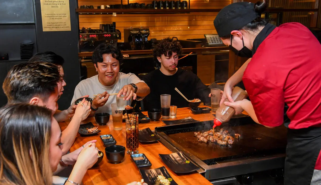 Pengunjung menikmati hidangan teppanyaki Jepang di Chinatown, Melbourne, Australia, Jumat (22/10/2021). Lima juta warga Melbourne kini akhirnya bisa keluar rumah lagi. (William WEST/AFP)