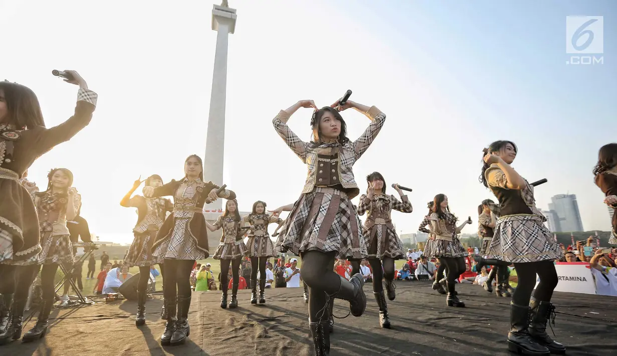Aksi para personel girlband JKT48 saat tampil dalam puncak Kirab Obor Asian Games 2018 di Monas, Jakarta, Sabtu (18/8). Obor Asian Games 2018 diarak dari Monumen Nasional (Monas) menuju Stadion Utama Gelora Bung Karno (SUGBK). (Liputan6.com/Faizal Fanani)