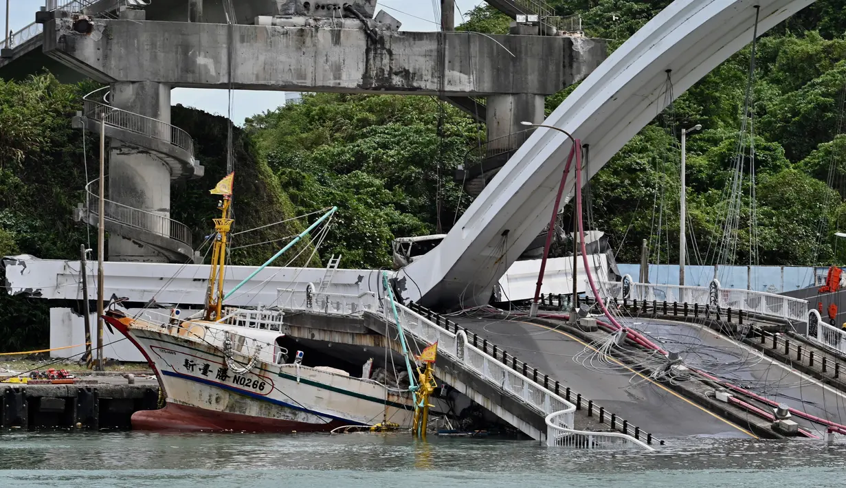 Sebuah kapal nelayan tertimpa jembatan beton yang ambruk di pelabuhan ikan Nanfangao di kota Suao (1/10/2019). Kejadian tersebut membuat setidaknya 14 orang terluka. (AFP Photo/Sam Yeh)