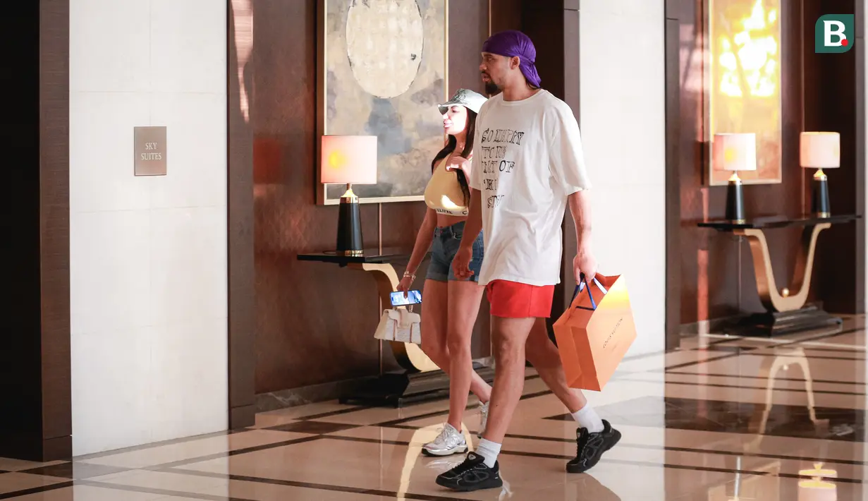 Pebasket Kanada, Dillon Brooks (tengah kanan) berjalan bersama sang kekasih, Danielle atau yang dikenal Big Bambina sambil membawa bungkusan di lobi hotel mereka menginap pada Kamis (24/08/2023). (Bola.com/Bagaskara Lazuardi)