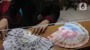 Petugas menunjukkan mata uang rupiah dan dolar di Jakarta, Senin (9/11/2020). Rupiah dibuka di angka 14.172 per dolar AS, menguat jika dibandingkan dengan penutupan perdagangan sebelumnya yang ada di angka 14.210 per dolar AS. (Liputan6.com/Angga Yuniar)