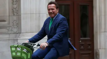 Gubernur California ke-38, Arnold Schwarzenegger tersenyum saat mengendarai sepeda untuk bertemu Walikota Paris, Anne HIdalgo di Paris (11/12). Schwarzenegger berada di Paris untuk menghadiri pertemuan puncak iklim One Planet. (AP Photo / Thibault Camus)