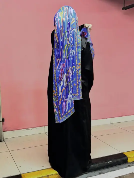 Foto tampak belakang, Sivia tampil dengan kerudung panjang warna biru bercorak dipadukan abaya hitamnya. [@siviazizah]