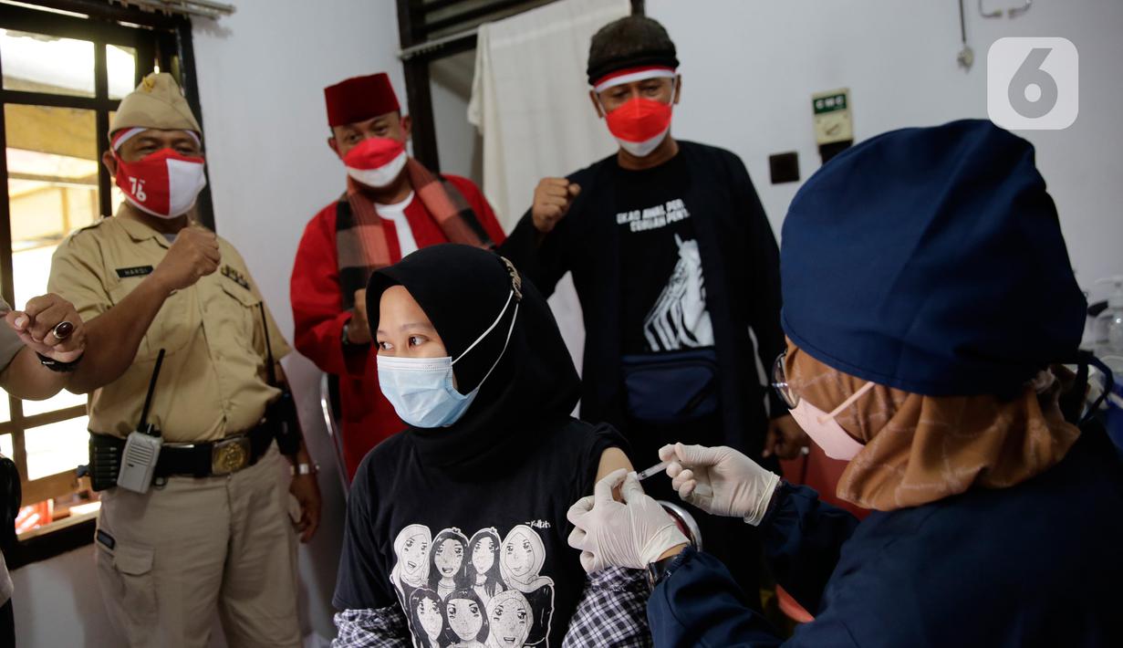 Petugas kepolisian berpakaian pejuang jaman dulu saat memberikan semangat kepada warga yang sedang divaksin Covid-19 di Polsek Pasar Rebo, Jakarta, Selasa (17/8/2021). Para petugas berkostum pejuang jaman dulu memeriahkan HUT ke-76 Republik Indonesia. (Liputan6.com/Angga Yuniar)