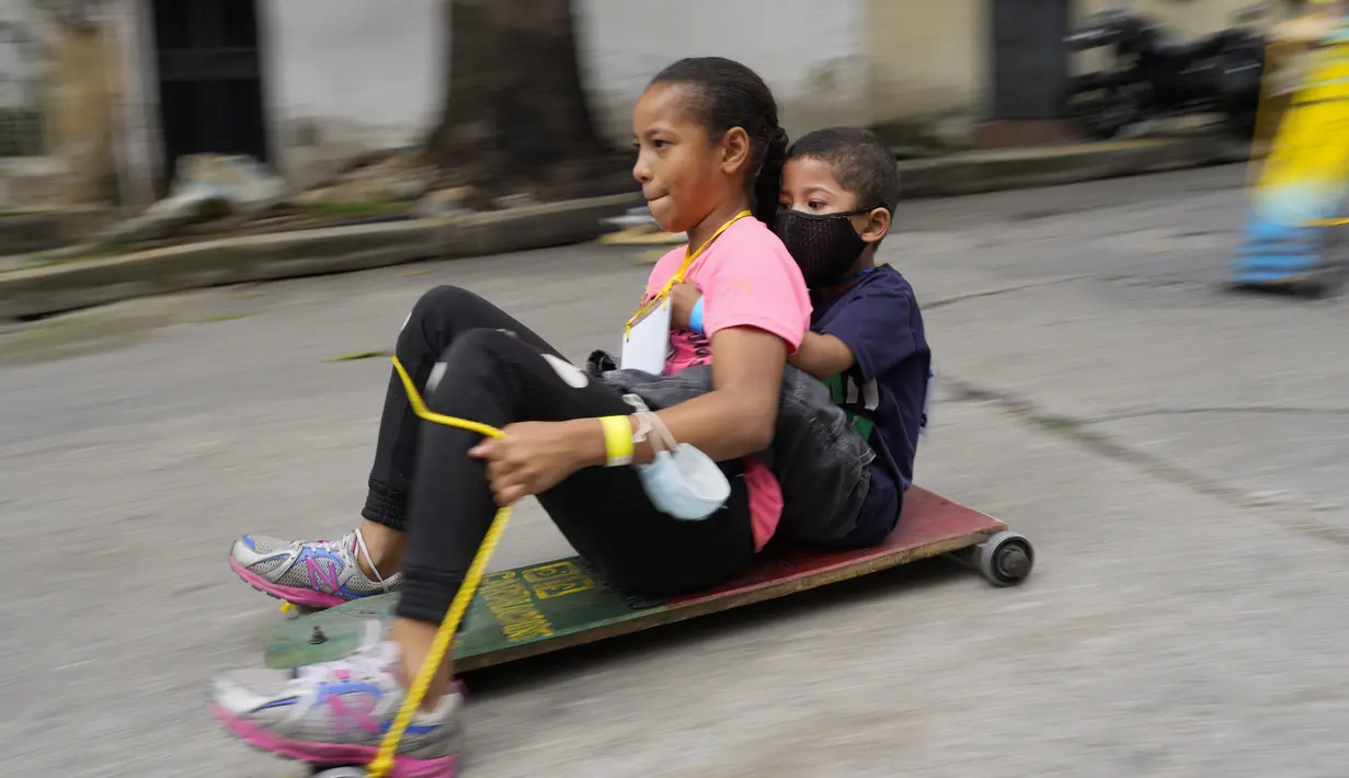 Anak-anak berpartisipasi dalam perlombaan jalanan tradisional "carruchas", sebutan untuk mobil kayu darurat di Caracas, Venezuela, Sabtu (18/12/2021). Anak-anak menikmati perlombaan yang menandai 10 tahun melestarikan tradisi ini. (AP Photo/Ariana Cubillos)