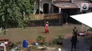 Warga melintasi banjir akibat jebolnya tanggul karena tertimpa tanah longsor, di Perumahan Nerada Estate Ciputat, Tangerang Selatan, Sabtu (12/6/2021). Longsor yang menimpa sejumlah rumah membuat tanggul pembatas kali jebol dan air meluap sehingga menyebabkan banjir. (Liputan6.com/Angga Yuniar)