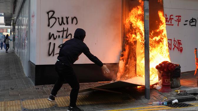 Seorang demonstran membakar kardus di luar cabang Bank of China selama protes di Distrik Central, Hong Kong, Senin (11/11/2019). Ketegangan di Hong Kong semakin meningkat setelah polisi menembak seorang demonstran hingga kritis. (AP Photo/Vincent Yu)