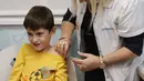 Bocah Israel, Yoav (9) menerima dosis vaksin Covid-19 Pfizer/BioNTech Covid-19 di Meuhedet Healthcare Services Organization di Tel Aviv, saat Israel memulai kampanye vaksinasi virus corona untuk anak berusia 5 hingga 11 tahun, Senin (22/11/2021). (JACK GUEZ / AFP)