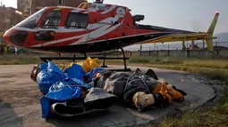 Jasad pendaki India yang tewas di  Everest diturunkan dari helikopter setibanya di ibu kota Nepal, Minggu (28/5). Jasad Ravi Kumar diterbangkan ke Kathmandu bersama dengan jasad dua orang lainnya yang meninggal tahun lalu. (AP Photo/Niranjan Shrestha)