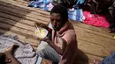 Seorang migran makan di geladak kapal penjaga pantai LSM Open Arms Spanyol setelah diselamatkan dari perairan terbuka selama operasi penyelamatan di zona perairan internasional di laut Mediterania, Rabu, 21 September 2022. (AP/Petros Karadjias)