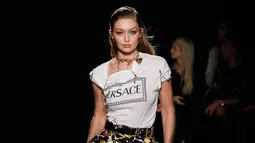 Model Gigi Hadid memperagakan busana koleksi Versace Pre-Fall 2019 di New York (2/12). Gigi tampil mengenakan t-shirt putih dengan logo Versace di bagian depan dipadukan dengan rok satin berwarna hitam, kuning dan putih. (AFP Photo/JP Yim)