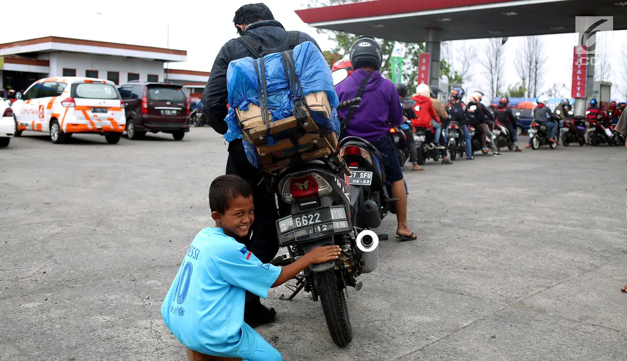 Seorang anak membersihkan motor yang di kendarai pemudik dari Jakarta menuju kampung halamannya di SPBU Tanjung Pantura - Brebes, Kamis (22/6). Memanfaatkan moment mudik anak - anak pantura mengais rejeki untuk lebaran 1438 H. (Liputan6.com/Johan Tallo)