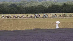Seorang wanita dengan gaun dan payung putih menonton balapan Tour de France etape ke-19 dengan jarak tempuh 222,5 km dari Embrun menuju Salon-de-Provence, Prancis, (21/7/2017). (AP/Christophe Ena)