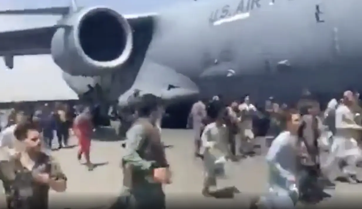 Ratusan orang berlari di samping pesawat angkut C-17 Angkatan Udara AS di landasan bandara internasional, di Kabul, Afghanistan (16/8/2021).  Ratusan warga Afghanistan berusaha kabur dari negaranya. Hal ini terjadi usai pemberontak Taliban menduduki ibu kota Afghanistan. (Verified UGC via AP)
