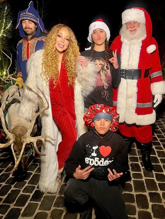 Mariah Carey merayakan Natal bersama keluarganya. Ia pun memilih mengenakan setelan piyama merah dipadukan coat berbulu warna putih. [@mariahcarey]