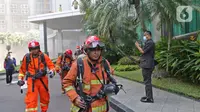 Petugas berlarian saat berusaha memadamkan kebakaran di Gedung Cyber 1, Jakarta, Kamis (2/12/2021). Sampai saat ini, penyebab kebakaran masih belum diketahui. (Liputan6.com/Herman Zakharia)