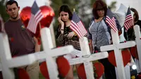 Sejumlah orang mengamati nisan untuk menghormati korban tewas penembakan massal yang terjadi dekat Kasino Mandalay Bay di Las Vegas, Jumat (6/10). Sebanyak 58 nisan kayu berbentuk salib itu ditambahkan ornamen hati berwarna merah. (AP/Gregory Bull)