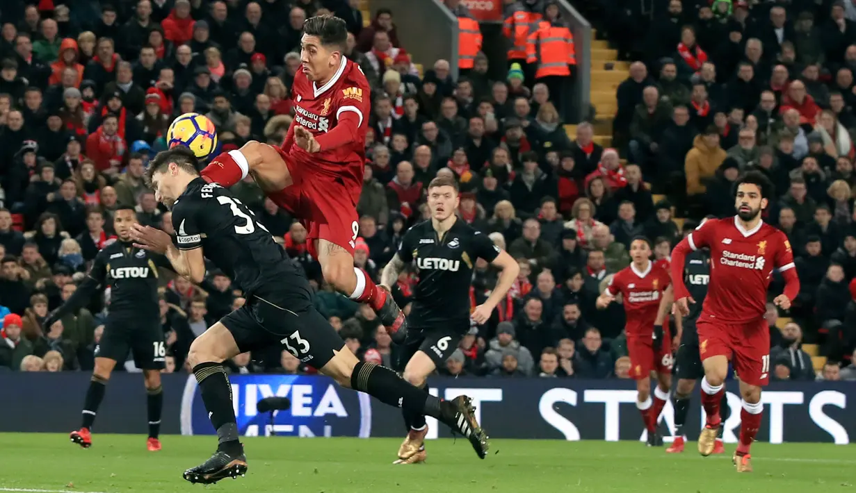 Pemain Liverpool, Roberto Firmino berebut bola dengan pemain Swansea City, Federico Fernandez pada laga pekan ke-20 Premier League di Stadion Anfield, Rabu (27/12). Dua gol Firmino membawa Liverpool menang lima gol tanpa balas.. (Peter Byrne/PA via AP)
