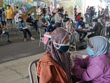 Warga menerima vaksinasi COVID-19 Sinovac di Terowongan Kendal, Jakarta Pusat, Jumat (30/7/2021). Sebanyak 600 dosis disiapkan untuk masyarakat pengguna transportasi publik di kawasan integrasi Commuter Line, kereta bandara, dan Transjakarta tersebut. (Liputan6.com/Faizal Fanani)