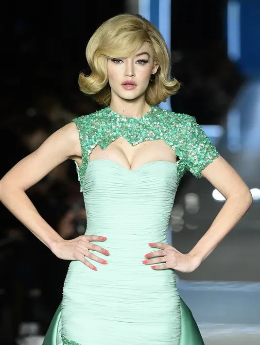 Model AS, Gigi Hadid berpose mengenakan koleksi terbaru Moschino di panggung runway Milan Fashion Week 2018, Rabu (21/2). Tampilan rambutnya dibuat bob khas Retro tahun 60-an yang disasak dan menggunakan poni. (Miguel MEDINA/AFP)