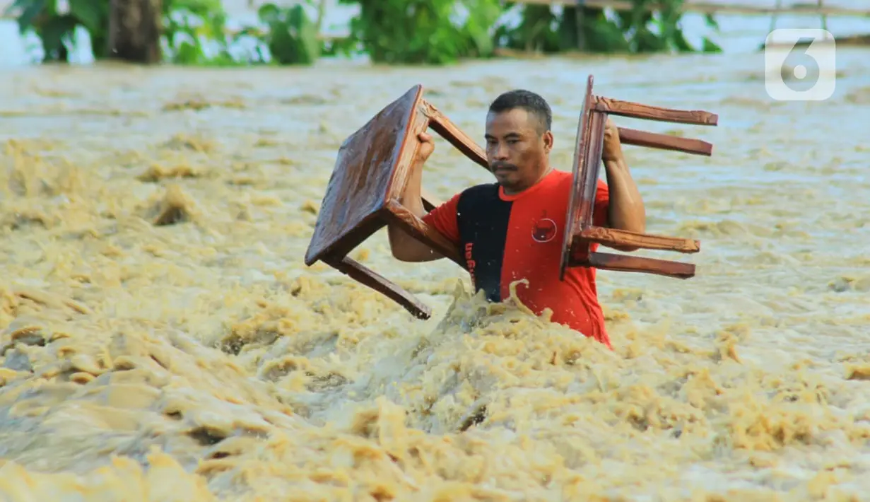 Warga membawa barang miliknya saat banjir bandang  di Kabupaten Bone Bolango, Gorontalo (11/6/2020). Data sementara yang diterima dari BPBD Kabupaten Bone Bolango sekitar 1.078 kepala keluarga serta 5.407 jiwa terdampak banjir bandang. (Liputan.com/Arfandi Ibrahim)