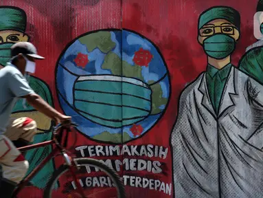 Pesepeda melintas di depan mural tentang pandemi virus COVID-19 di Jalan Raya Jakarta-Bogor, Depok, Selasa (7/4/2020). Mural tersebut ditujukan sebagai bentuk dukungan kepada tenaga medis yang menjadi garda terdepan menghadapi COVID-19 di Indonesia. (Liputan6.com/Helmi Fithriansyah)