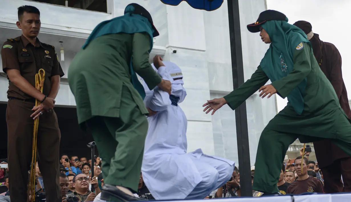 Petugas syariah mencambuk PSK online di halaman Masjid Jamik Lueng Bata, Banda Aceh, Aceh, Jumat (20/4). Gubernur Aceh Irwandi Yusuf mengeluarkan Pergub Nomor 5 Tahun 2018 Tentang Pelaksanaan Hukum Cambuk di Dalam Lapas. (CHAIDEER MAHYUDDIN / AFP)