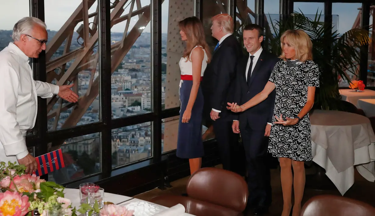 Koki Prancis Alain Ducasse mempersilahkan Presiden AS Donald Trump dan Melania Trump serta Presiden Prancis Emmanuel Macron dan istrinya, Brigitte Macron untuk jamuan makan malam di Menara Eifel, Paris, Kamis (13/7). (Yves Herman/Pool Photo via AP)