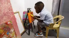 Ace-Liam Nana Sam Ankrah, yang akan berulang tahun ke dua pada bulan Juli, memamerkan tabung catnya di galeri seni ibunya di Accra, Ghana, pada 27 Mei 2024. (AP Photo/Misper Apawu)