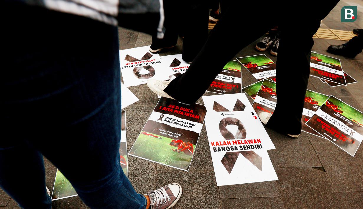 Poster-poster yang dibentangkan di trotoar jalan mendapat atensi dari warga dalam Aksi Duka 1 Juta Pita Hitam untuk Timnas Indonesia U-20 dan Piala Dunia U-20 di trotoar FX Sudirman, Jakarta, Jumat (31/3/2023). (Bola.com/M Iqbal Ichsan)