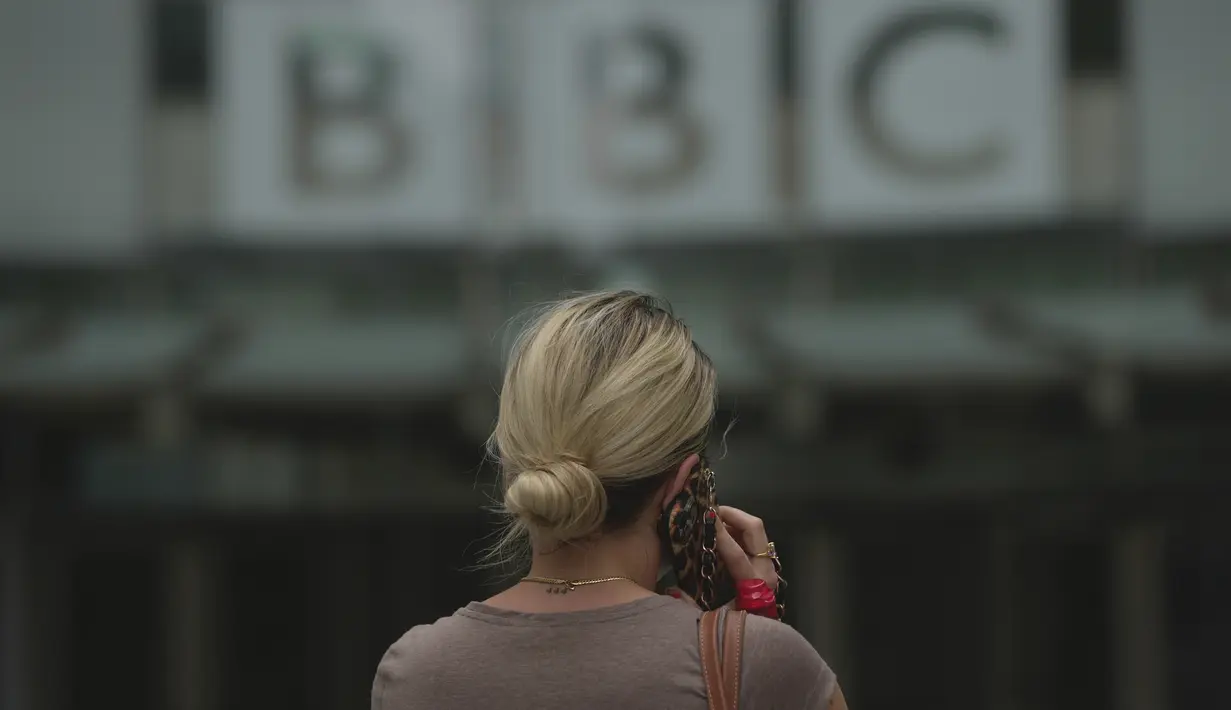 Seorang perempuan berjalan di luar Markas Besar BBC di London, Inggris, Selasa (11/7/2023). Detektif Inggris bertemu dengan perwakilan BBC pada hari Senin atas tuduhan bahwa seorang presenter terkemuka membayar seorang remaja untuk foto-foto eksplisit secara seksual. (AP Photo/Kin Cheung)