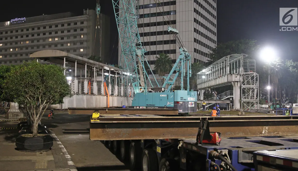 Petugas menggunakan alat berat merobohkan Jembatan Penyeberangan Orang (JPO) di Kawasan Bundaran Hotel Indonesia (HI), Jakarta, Senin (30/7/2018) malam. JPO dirobohkan karena menghalangi pandangan ke patung Selamat Datang. (Liputan6.com/Herman Zakharia)