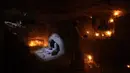 Seorang pria membaca ayat suci Al-Quran di makam kerabatnya di pemakaman Wadi al-Salam, di Najaf, selatan Baghdad, Irak, 28 Juli 2016. Pemakaman tersebut sudah ada sejak 1.400 tahun lalu. (REUTERS/Alaa Al-Marjani)