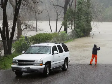 Seorang pria mengambil gambar kawasan yang banjir di sekitar Sungai Rusia di California, AS, Selasa (10/1). Kejadian itu memicu dievakuasinya lebih dari 3.000 orang penduduk dalam semalam di wilayah Guerneville. (AP Photo / Eric Risberg)