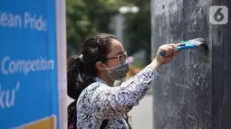 Pelajar membersihkan coretan yang mengotori tembok saat kericuhan dalam unjuk rasa di Senayan, Jakarta, Jumat (4/10/2019). Para siswa dan alumni SMA menutup coret-coretan  itu sekaligus mengampanyekan cinta damai dalam praktik demokrasi di Indonesia. (Liputan6.com/Immanuel Antonius)