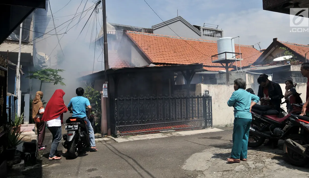 Warga menyaksikan petugas melakukan penyemprotan asap (fogging) nyamuk demam berdarah dengue (DBD) di RW 01, Kelurahan Cipinang, Jakarta, Minggu (10/3).   Fogging ini juga untuk membasmi perkembangbiakan jentik nyamuk. (merdeka.com/Iqbal Nugroho)